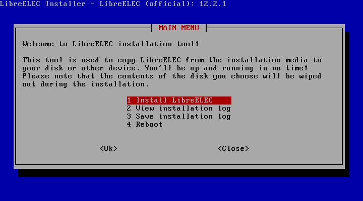 Layar alat instalasi teks LibreELEC Installer dengan menu utama berlatar biru berisi pilihan Install LibreELEC, View installation log, Save installation log, dan Reboot