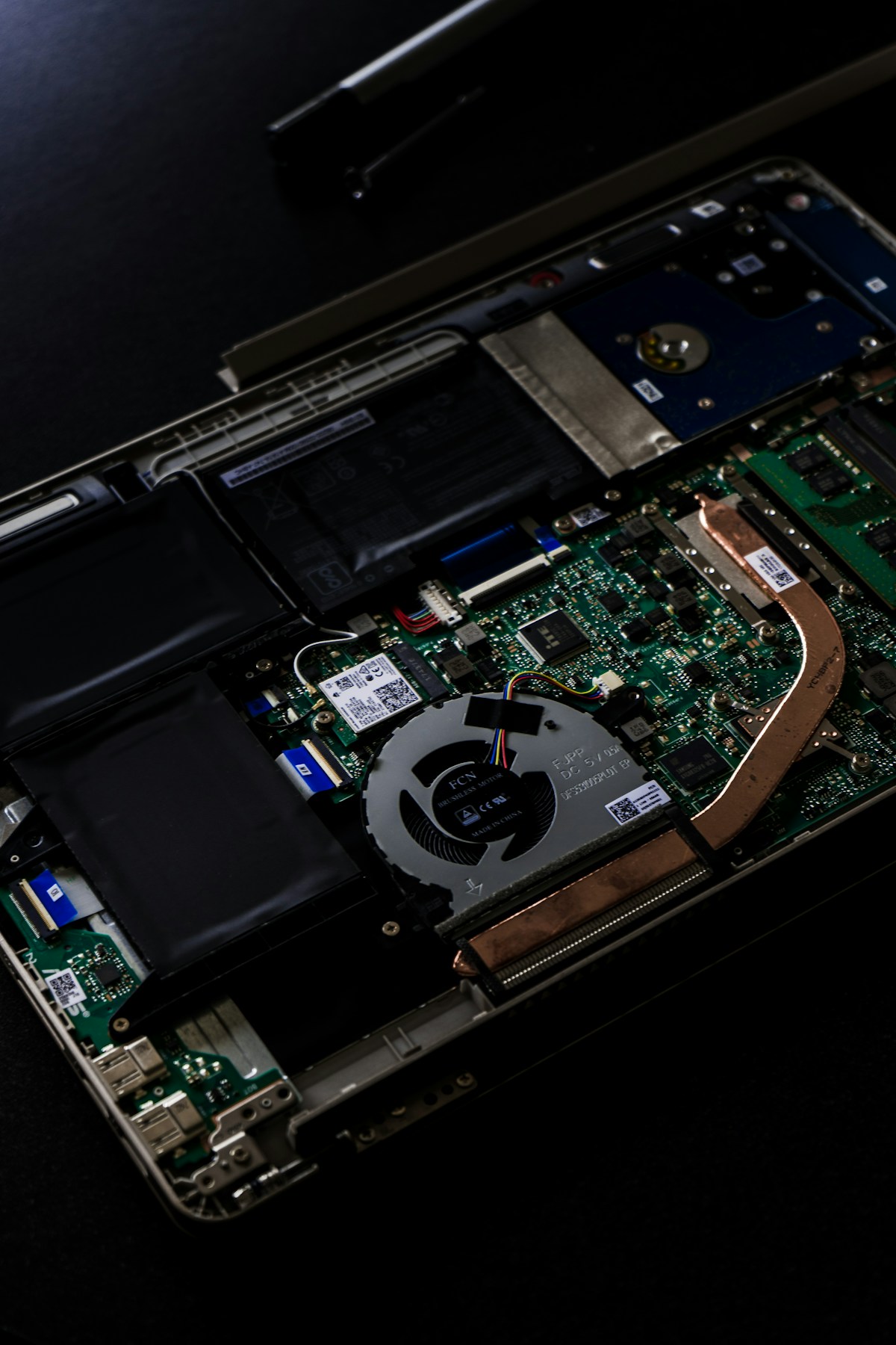 Interior laptop dibuka menampilkan komponen kipas, baterai, dan harddisk