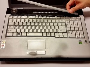 Langkah 2 — Angkat Penahan Plastik di Sisi Kiri Keyboard