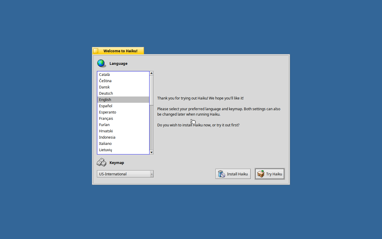 Jendela Welcome to Haiku menampilkan daftar pilihan bahasa dengan English terpilih, dropdown keymap US-International, serta dua tombol Install Haiku dan Try Haiku